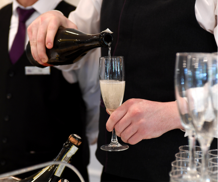 Pouring prosecco into a glass at a wedding